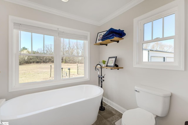 bathroom featuring a freestanding bath, toilet, crown molding, and baseboards