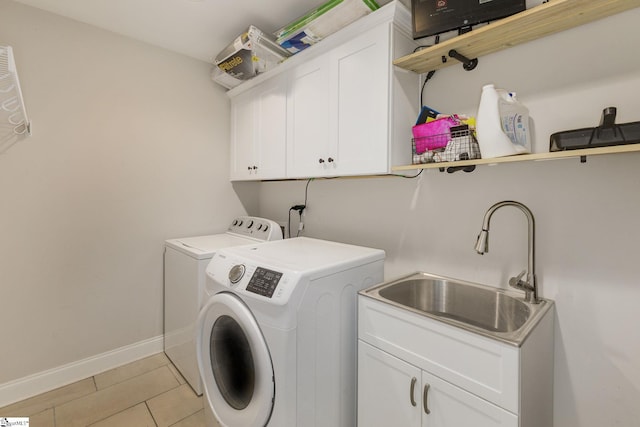 washroom with light tile patterned floors, baseboards, washing machine and clothes dryer, cabinet space, and a sink