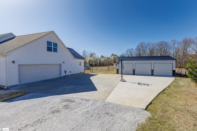 view of side of property featuring an outbuilding, concrete driveway, and fence