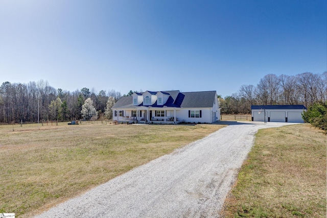 cape cod home with a detached garage, gravel driveway, covered porch, an outdoor structure, and a front yard