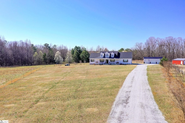 view of front facade featuring an outbuilding, fence, driveway, a front lawn, and a detached garage