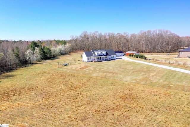 drone / aerial view featuring a view of trees and a rural view