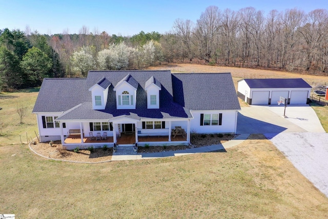 view of front of home with a porch, an outdoor structure, a front yard, a wooded view, and a garage