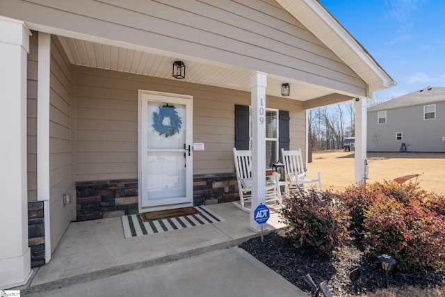 doorway to property with stone siding and covered porch