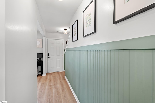 hall featuring light wood-style flooring and visible vents