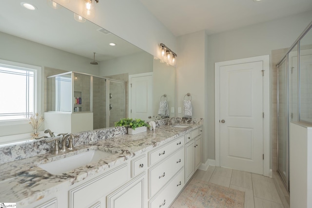 full bath featuring a shower stall, double vanity, tile patterned floors, and a sink