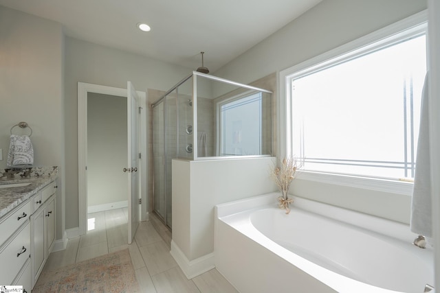 bathroom with a shower stall, baseboards, a garden tub, recessed lighting, and vanity