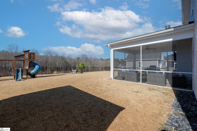 view of yard featuring a sunroom, a playground, and fence