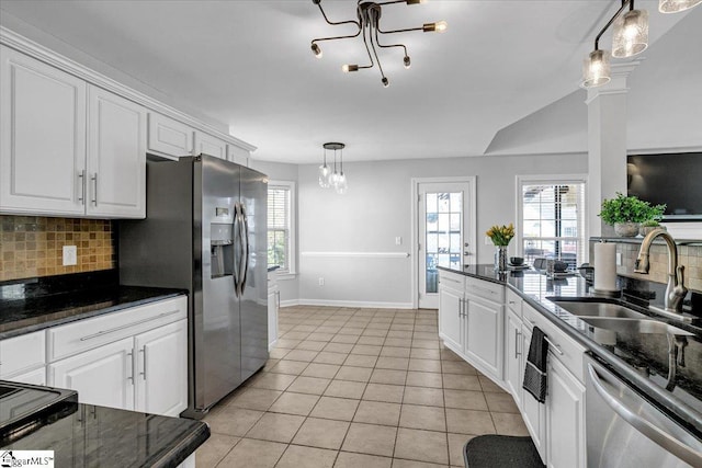 kitchen with decorative backsplash, stainless steel appliances, a notable chandelier, white cabinetry, and a sink