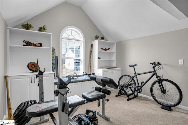 exercise area with vaulted ceiling, light colored carpet, and baseboards