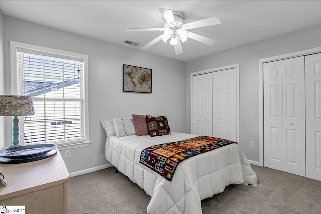 bedroom featuring carpet flooring, baseboards, visible vents, and two closets