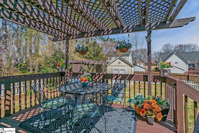 wooden deck with a residential view, a storage shed, outdoor dining area, an outbuilding, and a pergola