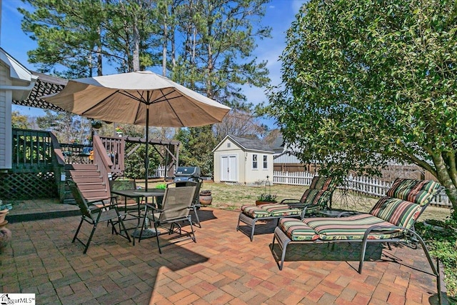 view of patio / terrace with a shed, a wooden deck, a fenced backyard, an outdoor structure, and outdoor dining space