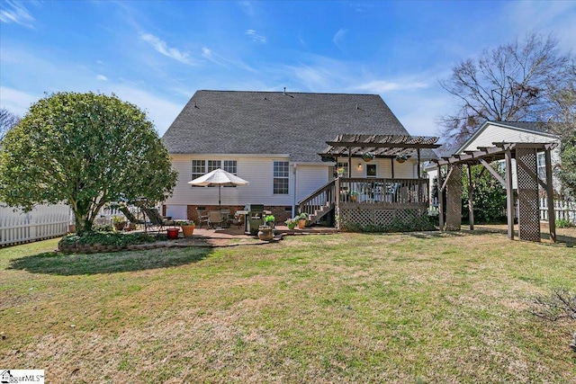 rear view of house featuring a wooden deck, a pergola, a yard, and fence