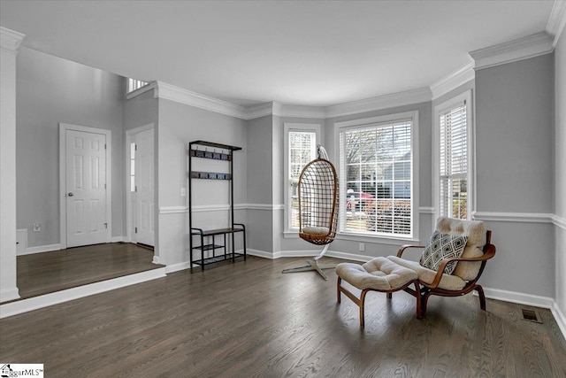 sitting room featuring visible vents, baseboards, wood finished floors, and ornamental molding