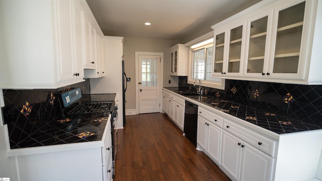 kitchen with a sink, black appliances, tile countertops, and white cabinetry