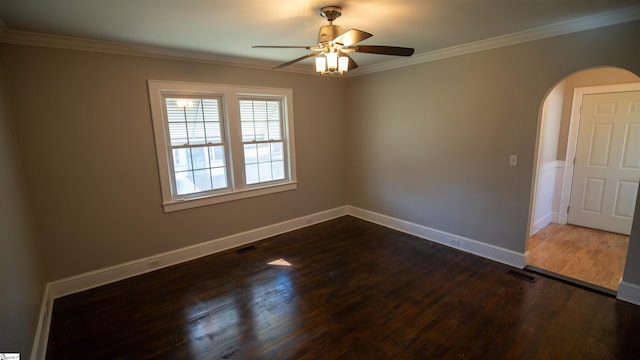 spare room with crown molding, baseboards, dark wood-type flooring, arched walkways, and a ceiling fan