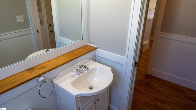 half bathroom featuring wainscoting, vanity, and wood finished floors