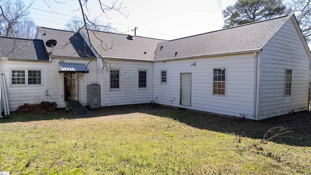 back of house featuring a yard and roof with shingles