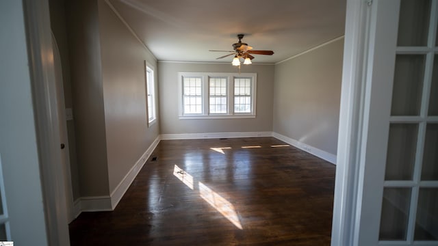 spare room with dark wood-type flooring, baseboards, crown molding, and ceiling fan