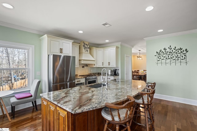 kitchen with visible vents, light stone countertops, ornamental molding, appliances with stainless steel finishes, and a sink