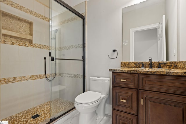 bathroom with a stall shower, toilet, and vanity