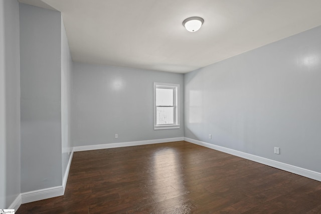 spare room featuring dark wood-type flooring and baseboards