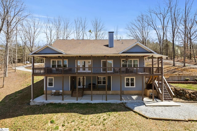 back of house with stairway, a chimney, a yard, a deck, and a patio area