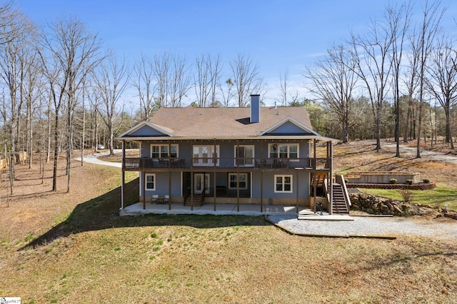 rear view of property featuring stairway, a chimney, a yard, a deck, and a patio