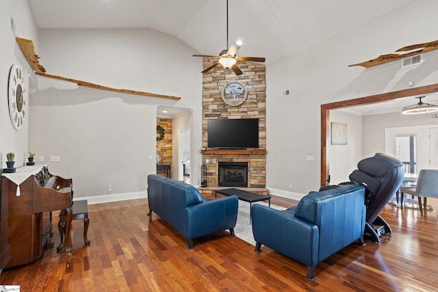 living room with a stone fireplace, wood finished floors, a ceiling fan, and visible vents