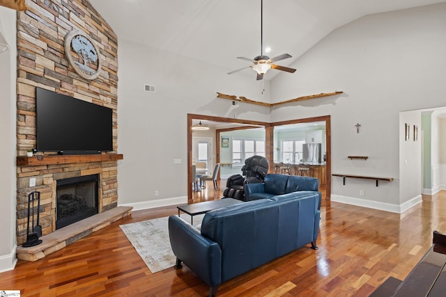 living room featuring visible vents, a stone fireplace, ceiling fan, and wood finished floors