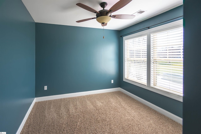 carpeted spare room featuring visible vents, ceiling fan, and baseboards