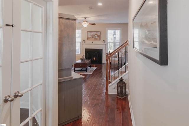 hallway featuring baseboards, dark wood-type flooring, and stairs