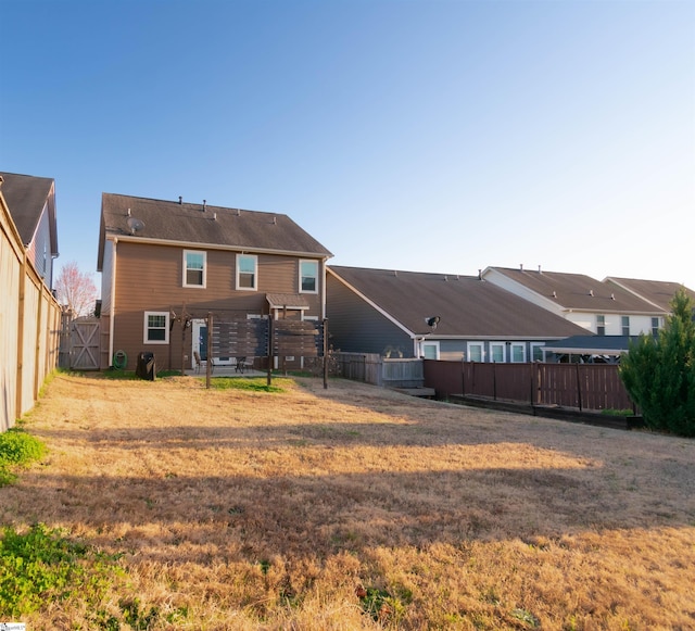 rear view of house with a fenced backyard and a lawn