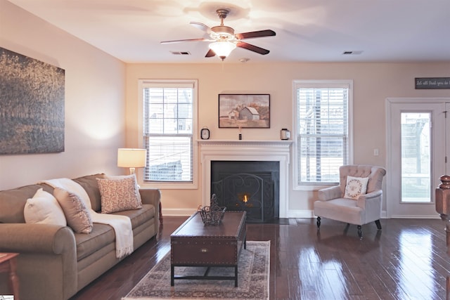 living room with hardwood / wood-style floors, visible vents, a fireplace with flush hearth, and ceiling fan