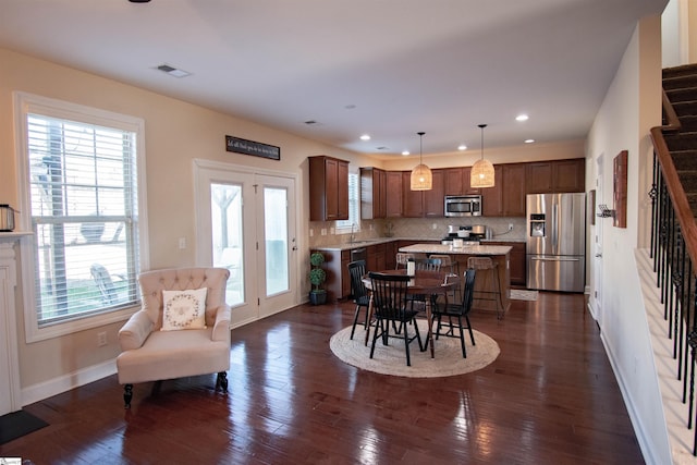 dining space featuring dark wood-style floors, visible vents, stairs, and baseboards