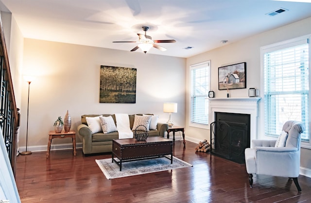 living area with visible vents, baseboards, a fireplace, wood finished floors, and a ceiling fan