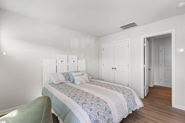 bedroom with visible vents, baseboards, lofted ceiling, a closet, and dark wood-style floors