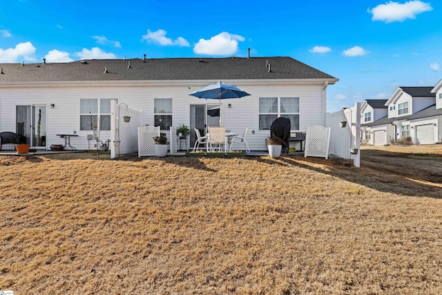 back of house with a patio, a lawn, and roof with shingles