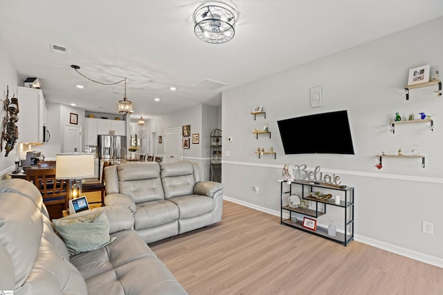 living room featuring recessed lighting, baseboards, visible vents, and light wood finished floors