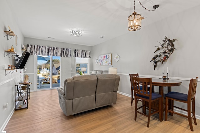 dining space featuring visible vents, baseboards, light wood-style floors, and a chandelier