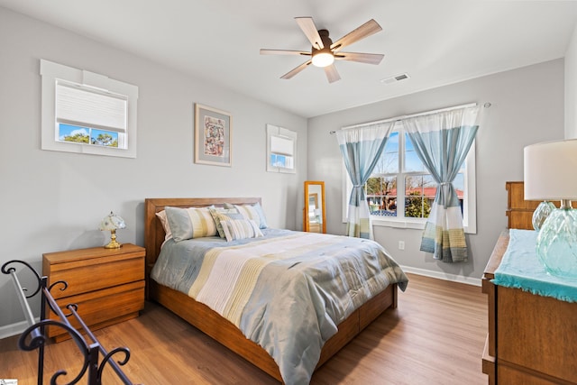 bedroom featuring visible vents, ceiling fan, baseboards, and wood finished floors