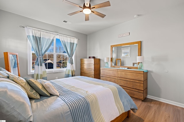 bedroom with visible vents, ceiling fan, baseboards, and wood finished floors