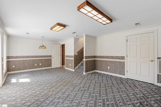 carpeted empty room with wallpapered walls, ornamental molding, visible vents, and wainscoting