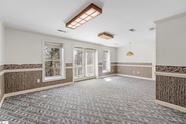 spare room featuring visible vents, wainscoting, crown molding, and carpet floors