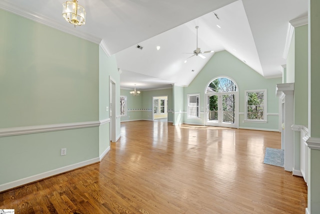 unfurnished living room with visible vents, high vaulted ceiling, ornamental molding, ceiling fan with notable chandelier, and wood finished floors