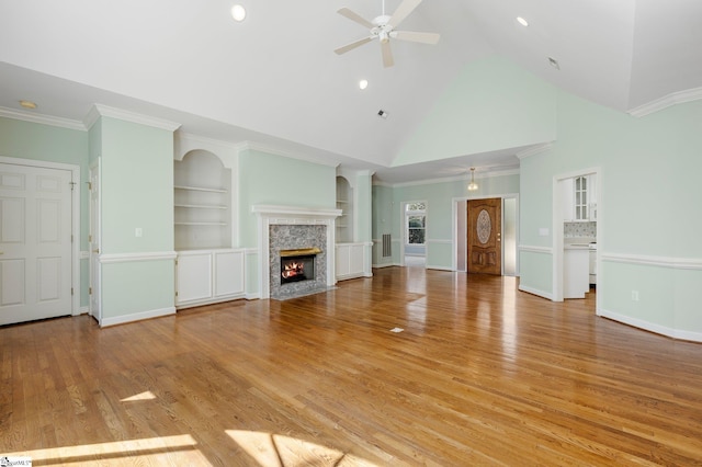 unfurnished living room with a premium fireplace, baseboards, light wood-style flooring, and a ceiling fan