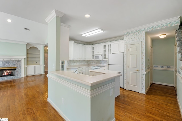 kitchen with glass insert cabinets, white appliances, a fireplace, and crown molding