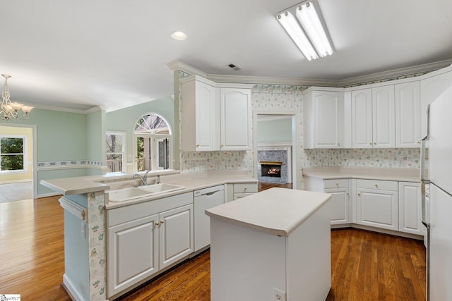 kitchen with visible vents, a kitchen island, ornamental molding, white appliances, and a sink