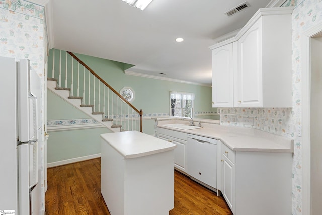 kitchen with a sink, white appliances, dark wood-style floors, and white cabinets